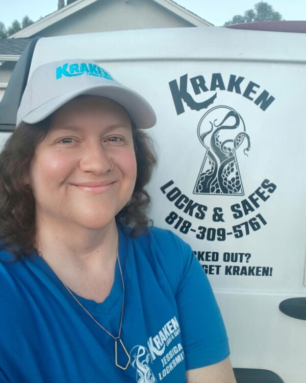 Jess Spencer, co-owner of Kraken Locks & Safes, wearing a Kraken cap beside the company service van